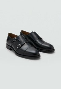 Black leather dress shoes with a rounded toe, featuring two silver buckles across the upper and a low stacked heel. Smooth texture and clean lines.
