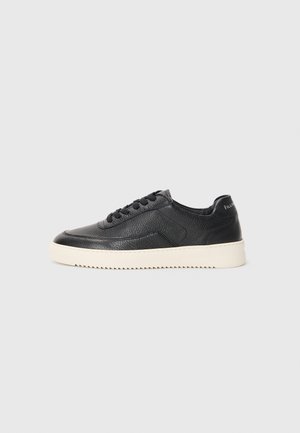 Must be a black leather sneaks, millelööb, ümar ninaga ja lame valge kummitald. Omab musti paelu ja brändingut kanna peal.