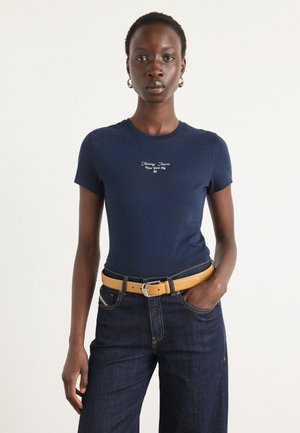T-shirt en coton bleu marine avec un col rond, des manches courtes et le texte blanc "Tommy Jeans New York City" sur la poitrine. Porté avec un pantalon en denim foncé.