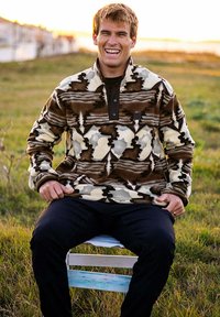 Pull en polaire marron, crème et gris avec motif camouflage ; col à deux boutons ; manches longues ; coupe décontractée ; porté avec un pantalon foncé.