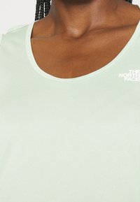 Ljusgrön linne i mjukt tyg. Har rund halsringning och en liten vit logga på vänster sida.