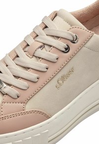Baskets rose clair et beige avec suède texturé et cuir lisse, dotées d'un système de laçage à l'avant, d'œillets en métal et d'un logo embossé sur le côté.