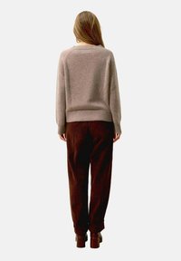 Brązowe spodnie kordurojowe i jasnoszara wełniana sweter z prążkowanym dołem, widok z tyłu. Materiał wydaje się miękki i przytulny.