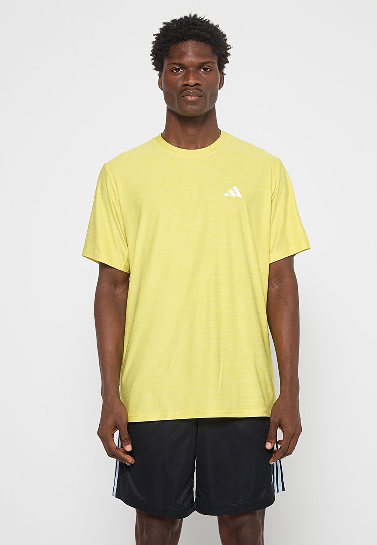 T-shirt de sport jaune avec un col rond, des manches courtes et un motif texturé subtil. Présente un petit logo blanc sur la poitrine.
