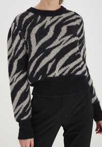 Svart och grårandig tröja med en mjuk textur, ribbade mudd och nederkant. Har en bred rund halsringning och en avslappnad passform.