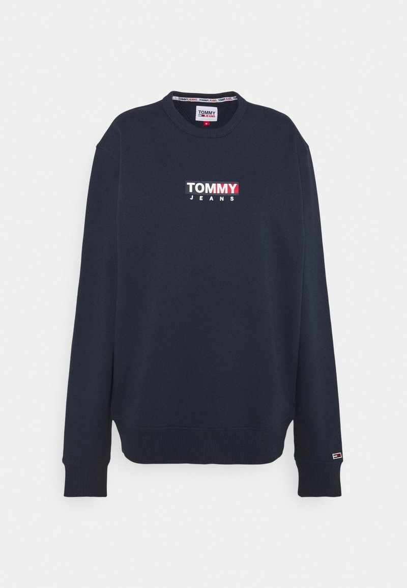 Sudadera de un oscuro color navy con cuello redondo, que presenta un logo "TOMMY JEANS" en blanco y rojo en el pecho. Puños y dobladillo acanalados. Textura suave.