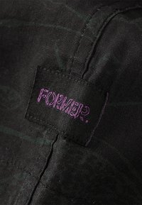 Black fabric with a subtle green pattern featuring a purple label that reads "FORMER?" Text is stylized and positioned on a seam.