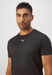 Donkergrijze T-shirt met korte mouwen, gemaakt van een gladde stof, met een klein wit Puma-logo dat gecentreerd op de borst is.