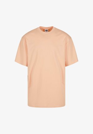 T-shirt à manches courtes couleur pêche clair en coton. Il dispose d'un col rond et d'une coupe décontractée. Texture lisse sans motifs ni graphismes.