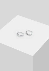Orecchini d'argento con due design distinti: un orecchino ad anello curvo liscio e un altro con una fascia testurizzata impreziosita da piccoli accenti circolari.