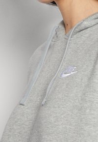 Grå hoodie med dragsko och ljusblå detaljer. Märkbar Nike-logga i ljusblått broderad på bröstet. Mjuk och skön tygkvalitet.