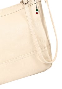 Beige leren schoudertas met een gestructureerde afwerking, voorzien van een afneembare band en een klein Italiaans vlaggetje als hanger.