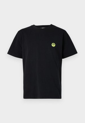 Juodas medvilnės marškinėliai trumpomis rankovėmis, su nedideliu apvaliu neoninės žalios spalvos piešiniu, vaizduojančiu šypsenėles su iltimis, kairėje krūtinės pusėje.