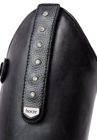 Bota de montar de cuero negro con punta redondeada, que cuenta con una correa decorativa con cinco tachuelas plateadas y una etiqueta con el logo "horze".