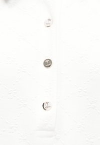 Tissu blanc avec une broderie florale subtile et trois boutons métalliques gravés d'un logo d'arbre et du mot "JOOP!".