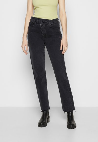 Black straight-leg jeans made of denim with a slightly faded finish, featuring five pockets and a frayed hem. Paired with a light green top.
