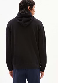 Felpa nera in cotone con tasca a marsupio, polsini e orlo a costine, dotata di cappuccio con cordino e una texture liscia e morbida.