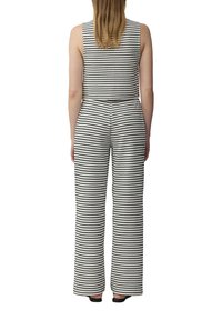 Gestreepte jumpsuit in zwart en wit, mouwloos ontwerp met een aansluitend lijfje en wijde broekspijpen. Glad textuur van de stof met verticale strepen.