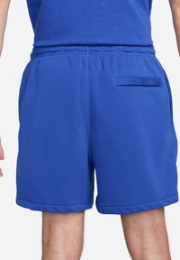 Shorts blu in felpa realizzati in tessuto morbido, dotati di una cintura elasticizzata, tasche laterali e una tasca posteriore con un design minimalista.