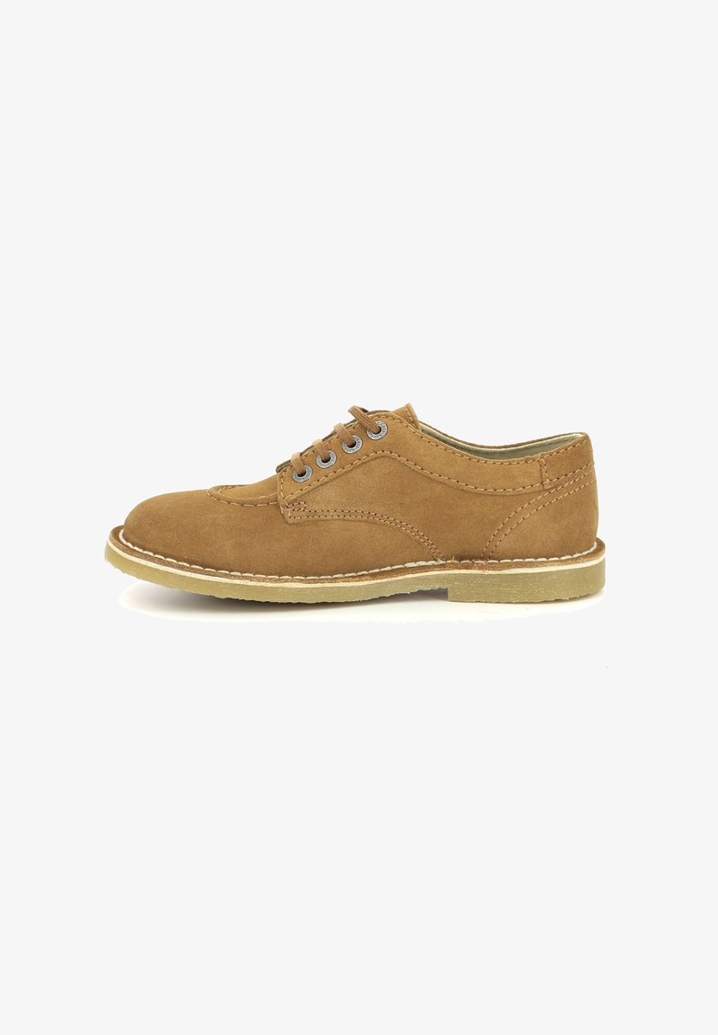 Chaussure en suède beige avec un bout rond, cinq œillets et une semelle en caoutchouc clair. Présente des coutures décoratives le long des bords.