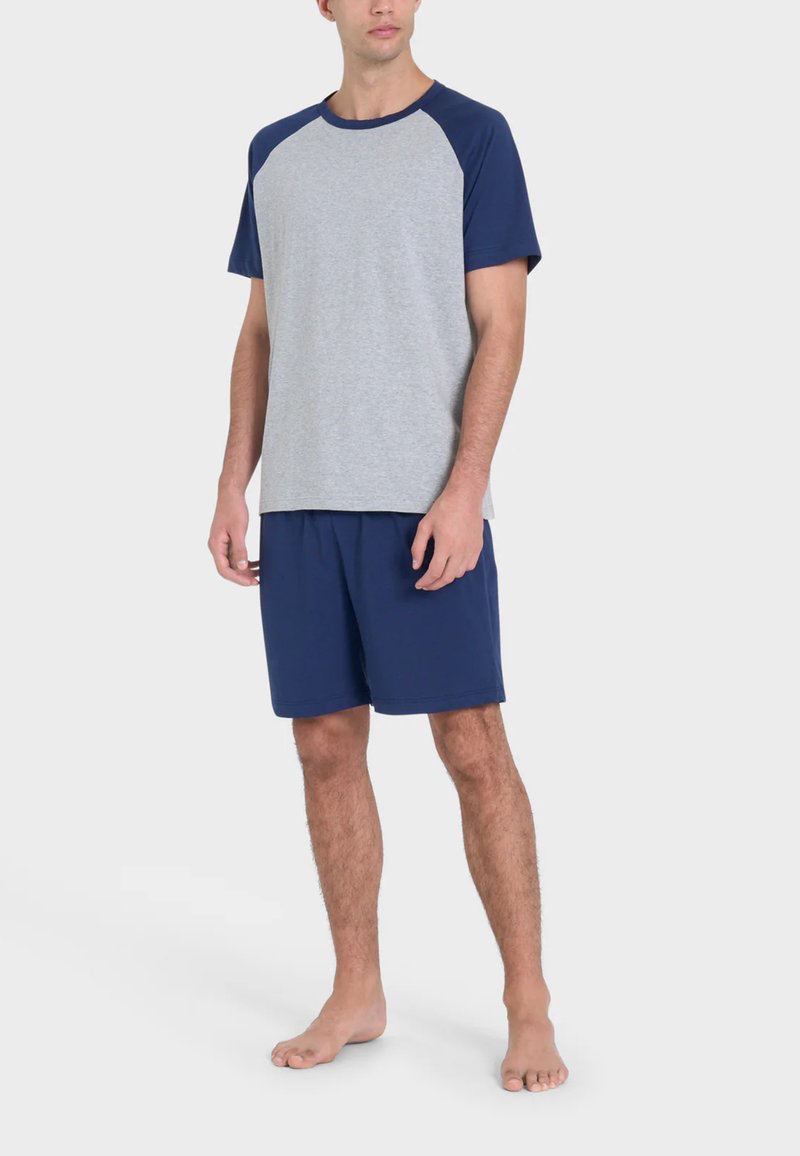 T-shirt grigia con maniche raglan blu navy abbinata a shorts blu navy. Tessuto in cotone, vestibilità standard, senza motivi o accenti visibili.