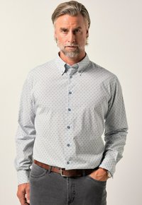 Světle modrá košile s knoflíky, s jemným vzorem, dlouhými rukávy a límečkem. Viditelné šedé kalhoty a hnědý opasek.