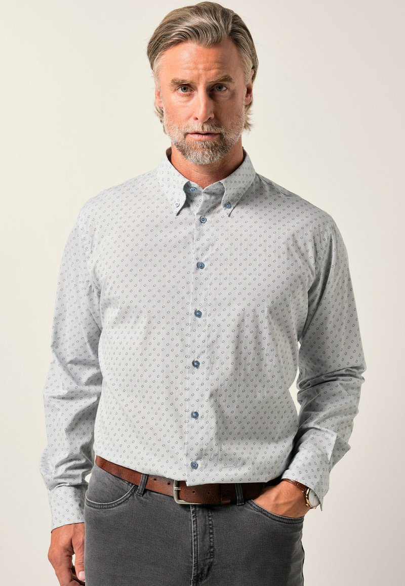 Světle modrá košile s knoflíky, s jemným vzorem, dlouhými rukávy a límečkem. Viditelné šedé kalhoty a hnědý opasek.