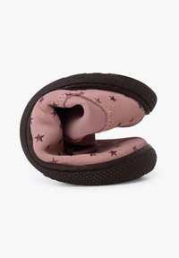 Zapato de tela rosa con un patrón de estrellas, diseño flexible y suela de goma oscura texturizada. El zapato está enrollado para mostrar su suavidad y forma.