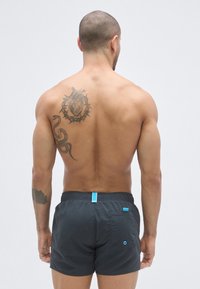 Ανδρικά μαγιό σορτς σε σκούρο γκρι, με ελαστική μέση και μπλε λεπτομέρεια. Οπίσθια τσέπ�η με αντίθετο μπλε στοιχείο.