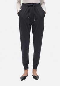 Pantalones jogger gris oscuro hechos de tela suave, con cintura ajustable, bolsillos laterales, piernas ajustadas y puños acanalados.