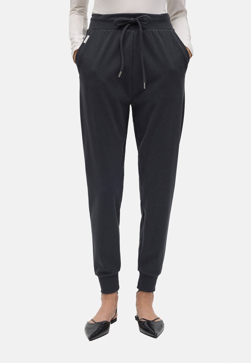 Pantalones jogger gris oscuro hechos de tela suave, con cintura ajustable, bolsillos laterales, piernas ajustadas y puños acanalados.