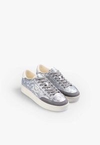 Srebrne i szare sneakersy o teksturowanym wykończeniu, z białym wzorem czaszki, szarymi zamszowymi akcentami, okrągłym noskiem i szarymi sznurowadłami na białej podeszwie.