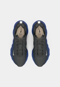 Αθλητικά παπούτσια Nike με σκούρο γκρι άνω μέρος, μπλε λεπτομέρειες, υφή επιφάνειας, σχέδιο με κορδόνια και διάτρητες λεπτομέρειες. Το λογότυπο Nike είναι ορατό στο πλάι.