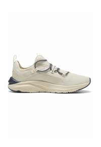 Zapatilla deportiva color crema con una parte superior de malla transpirable, cordones elásticos y una suela de goma azul marino. Presenta un diseño suave y redondeado.