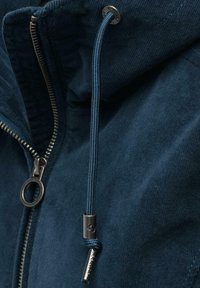 Marineblå hættetrøje med metallynlås og snor med stropper, lavet af tekstureret stof med en blød finish. Detaljer inkluderer en rund lynlåstræk.