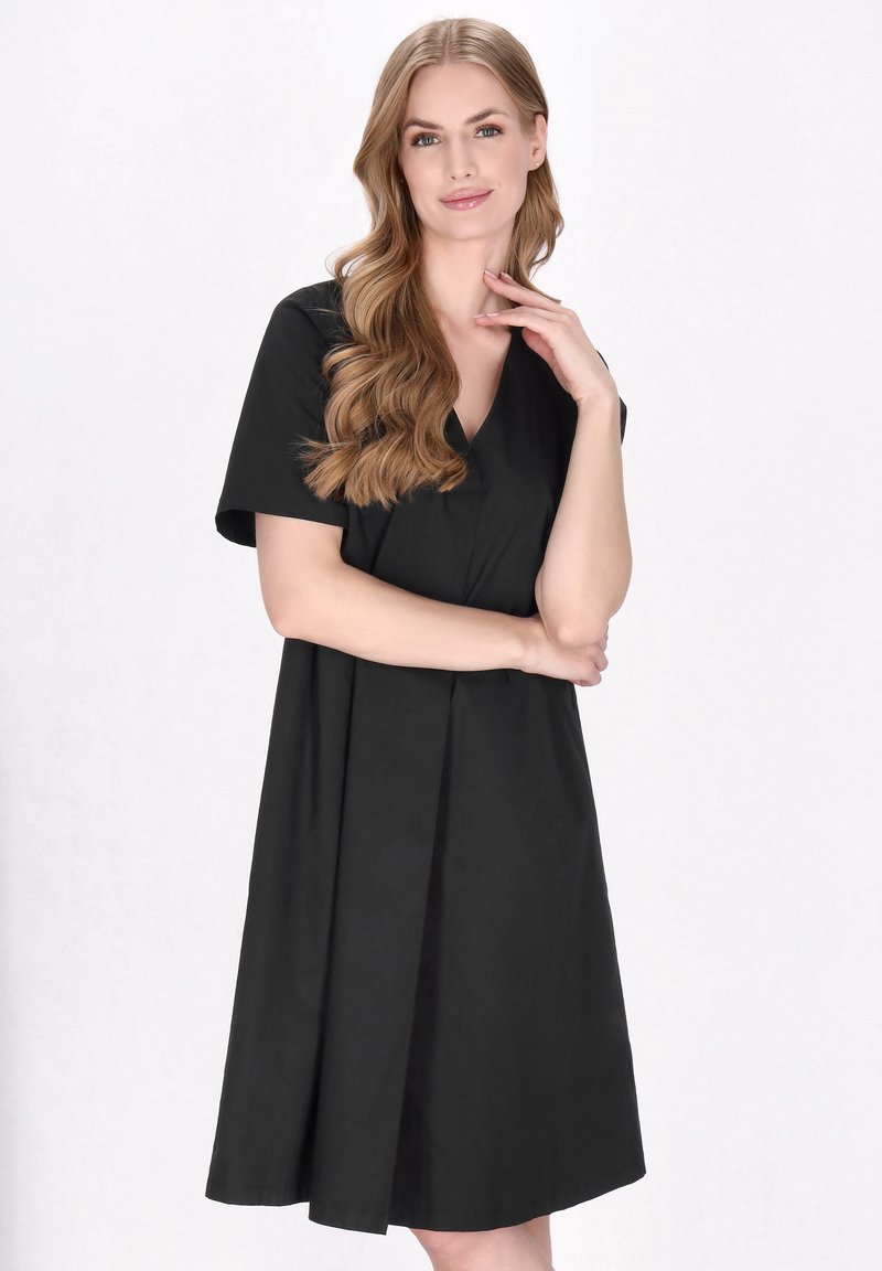 Schwarzes A-Linien-Kleid mit V-Ausschnitt, kurzen Ärmeln und fließender Silhouette. Hergestellt aus glattem Stoff mit weicher Textur.