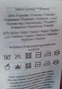 Verzorgingslabel voor textiel met vezelinhoud: 26% polyester, 22% nylon. Bevat was-, droog- en strijksymbolen in meerdere talen.