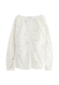 Vit långärmad topp med båthals, prydd med delikat blommönsterbroderi och små paljetter över tyget för extra textur.