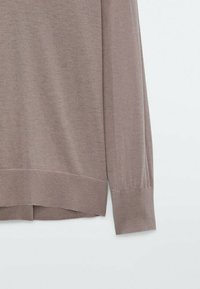 Pull léger couleur marron clair avec une texture douce, des poignets et un ourlet côtelés, et une coupe décontractée. Présente un design simple et minimaliste.