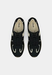 Pair of black and white Clarks Signature sneakers with laces, viewed from above on a white background.