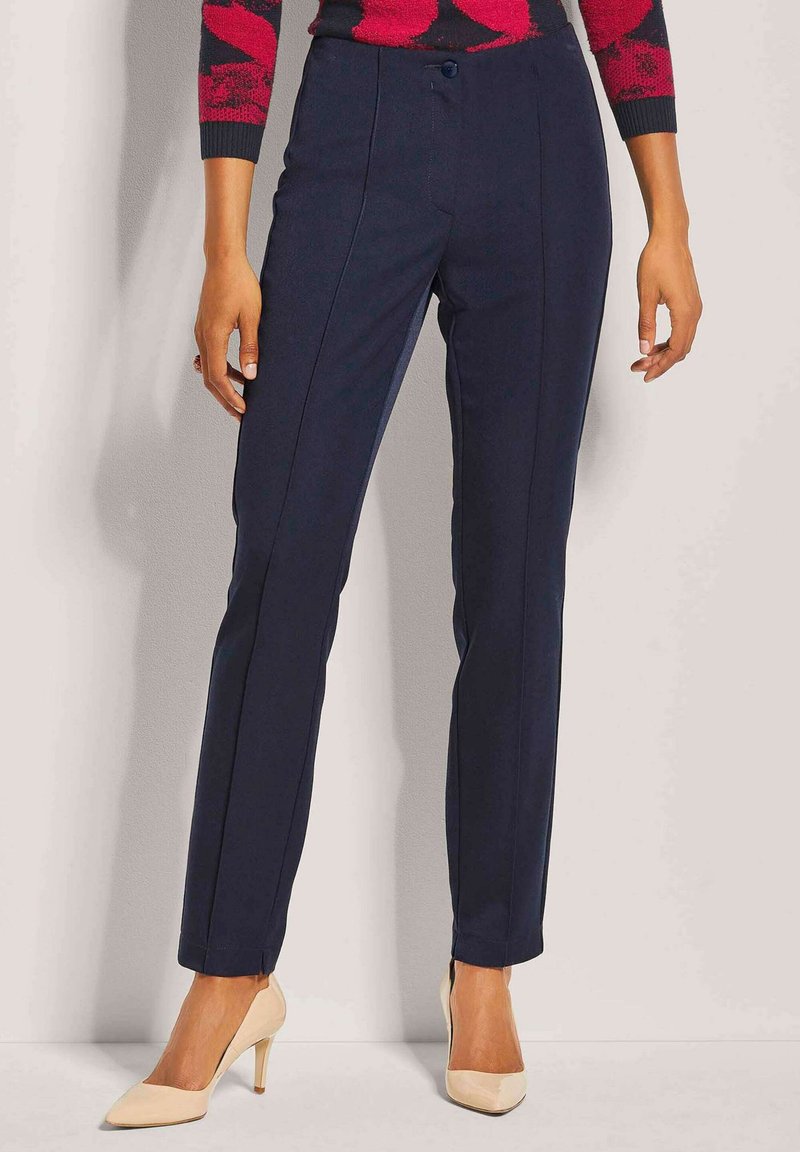 Marineblauwe broek met een recht model, voorzien van plooien, een knoopsluiting en een soepele textuur, gecombineerd met lichtgekleurde hoge hakken.