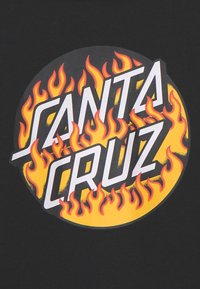 Camiseta negra con un logo circular que presenta el texto "Santa Cruz" en letras blancas en negrita, rodeado de llamas rojas sobre un fondo amarillo.
