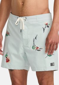 Light blue swim shorts with floral embroidery in red, green, and black. Features a drawstring waist and small logo at the hem.
