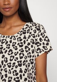 Leopard print t-shirt in cream and black, featuring a round neckline and short sleeves, made of soft fabric with a smooth texture.