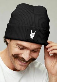 Black ribbed beanie with a fold-over cuff featuring a white graphic of a hand making the "rock on" gesture on a square patch.