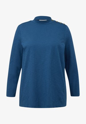 Niebieska bluzka z długim rękawem i wysokim kołnierzem, z czterema złotymi guzikami na lewym ramieniu oraz miękkim, teksturowanym materiałem.