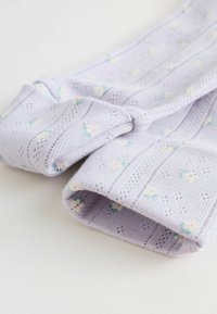 Lila stickade strumpor med små blommönster, ribbade muddar och en strukturerad yta. Materialet verkar mjukt och lätt.