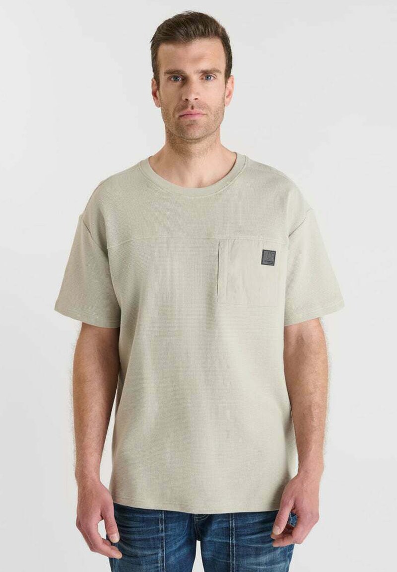 Lichtbeige textuur T-shirt met een ronde halslijn, korte mouwen en een borstzak met een zwart labeldetail.