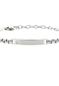 Bracciale in metallo argentato con una placca liscia e curva caratterizzata da un motivo texturizzato e una piccola pietra incastonata, collegata da una catenina.