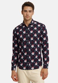 Knopfleiste Hemd in Dunkelblau mit einem Druck von Weihnachtsmann-Gesichtern, roten Texten und grünen Akzenten. Weicher Stoff mit einer taillierten Passform.